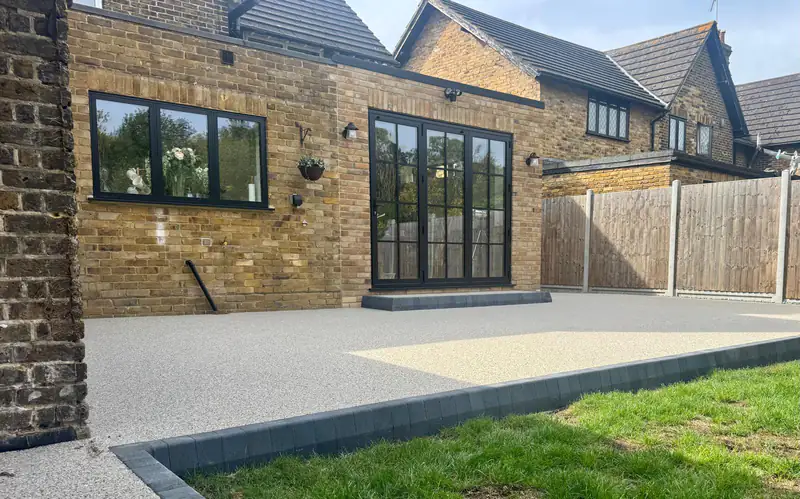 Resin bound patio wrapping around a house extension, edged against the lawn