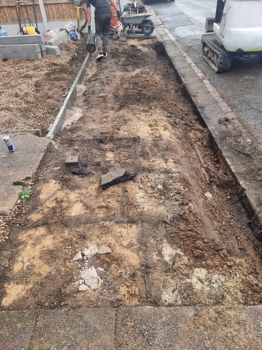 Front garden dug out for a new drive, with edging kerbs being set and a mini digger on site