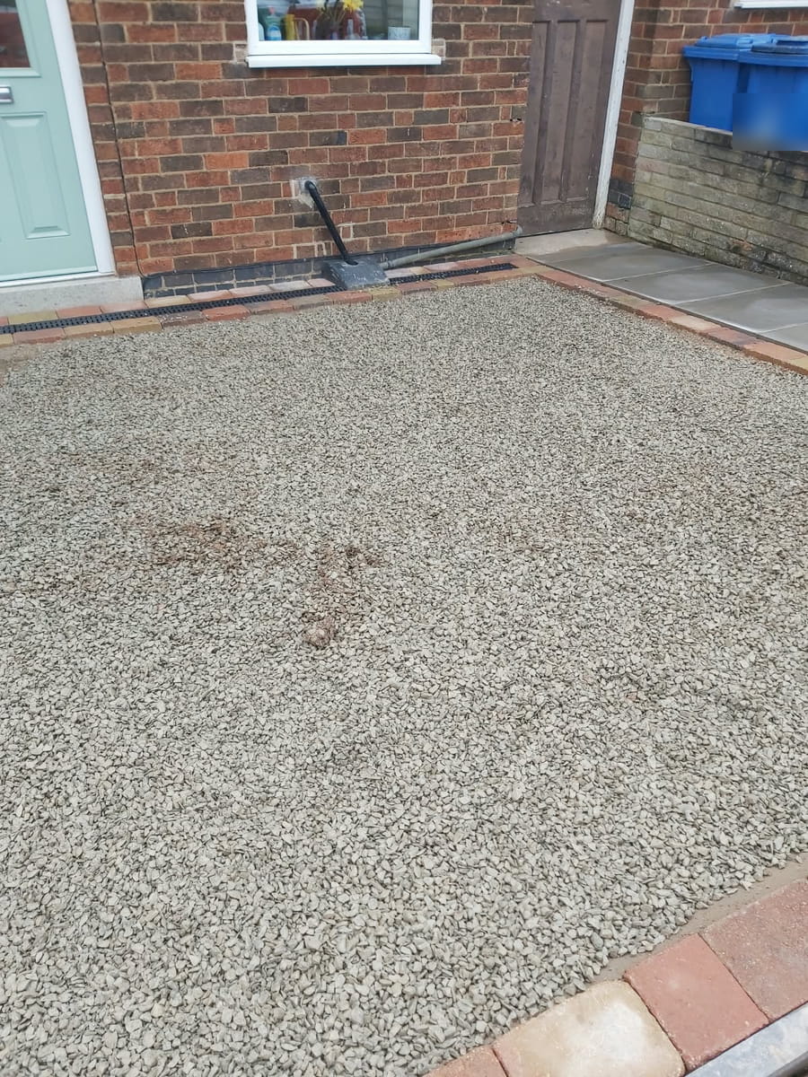 Stone sub-base laid right up to the channel drain along the front of the house
