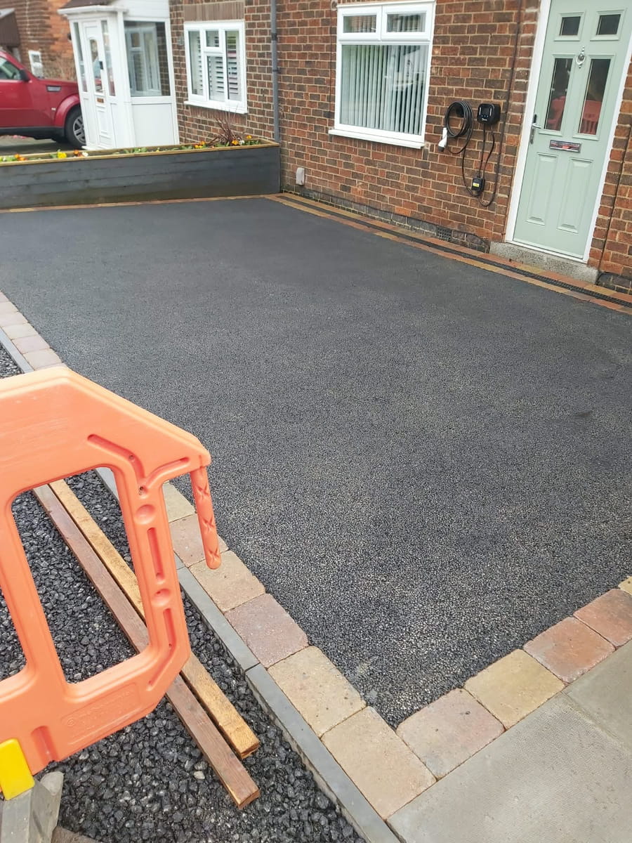 Finished tarmac drive in front of the house, edged with block paving