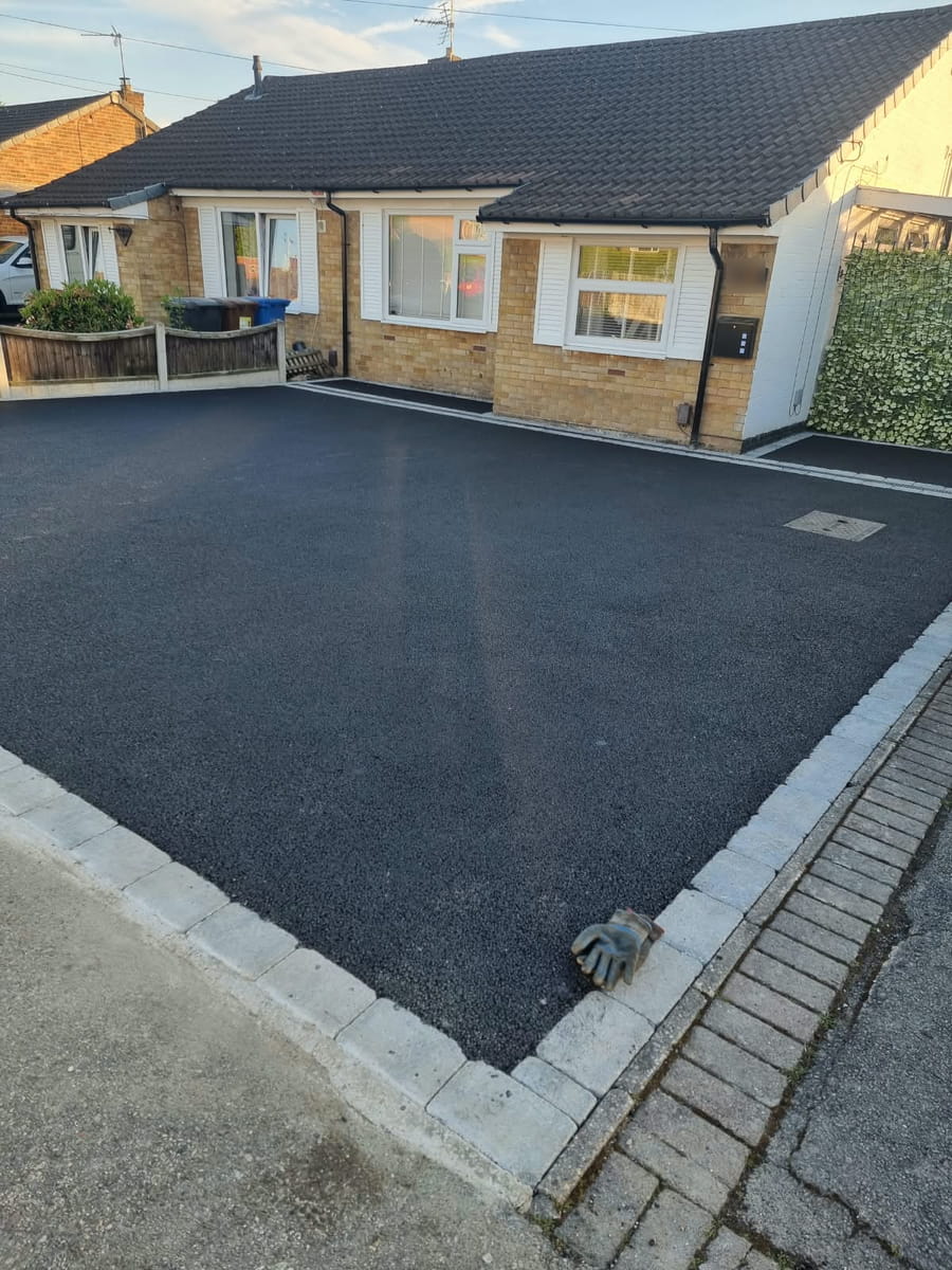 Finished tarmac drive in front of a bungalow, with block edging where it meets the pavement