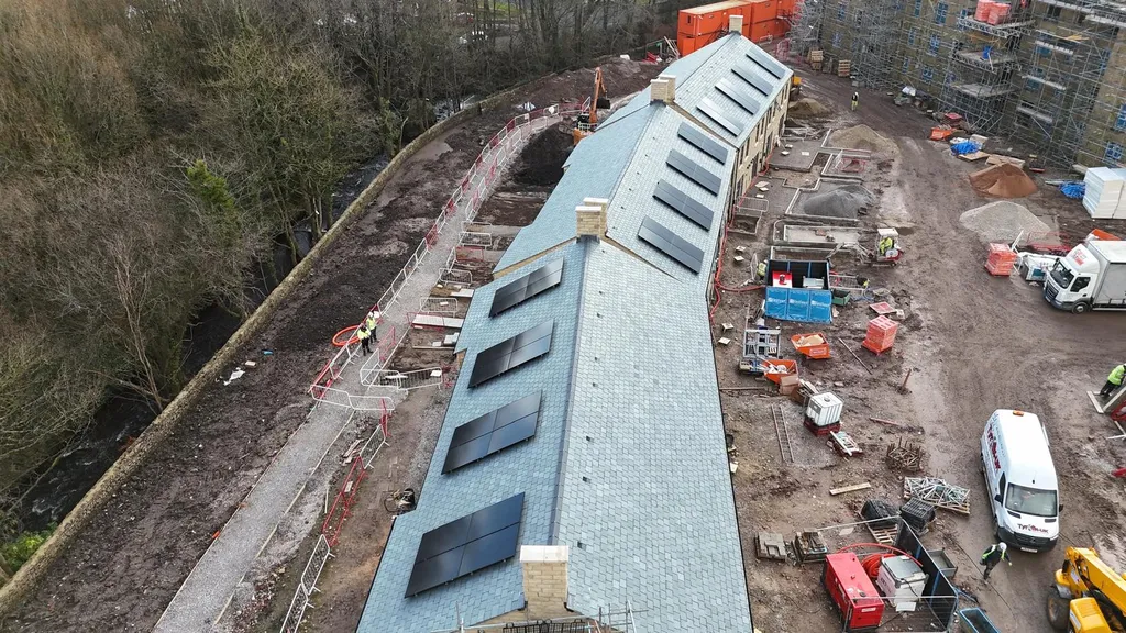 New-build apartments with solar panels — riverside drone, Manchester