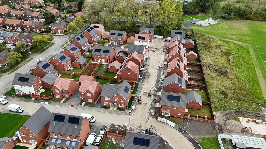 New-build estate solar panels with sports field — aerial, Manchester