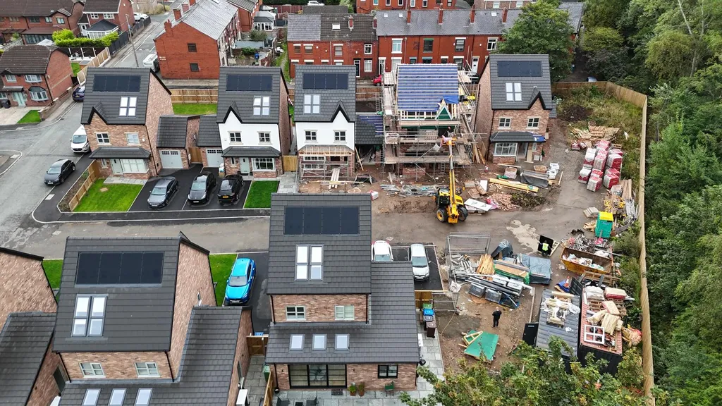 New-build housing development with solar panels — wide drone, Manchester