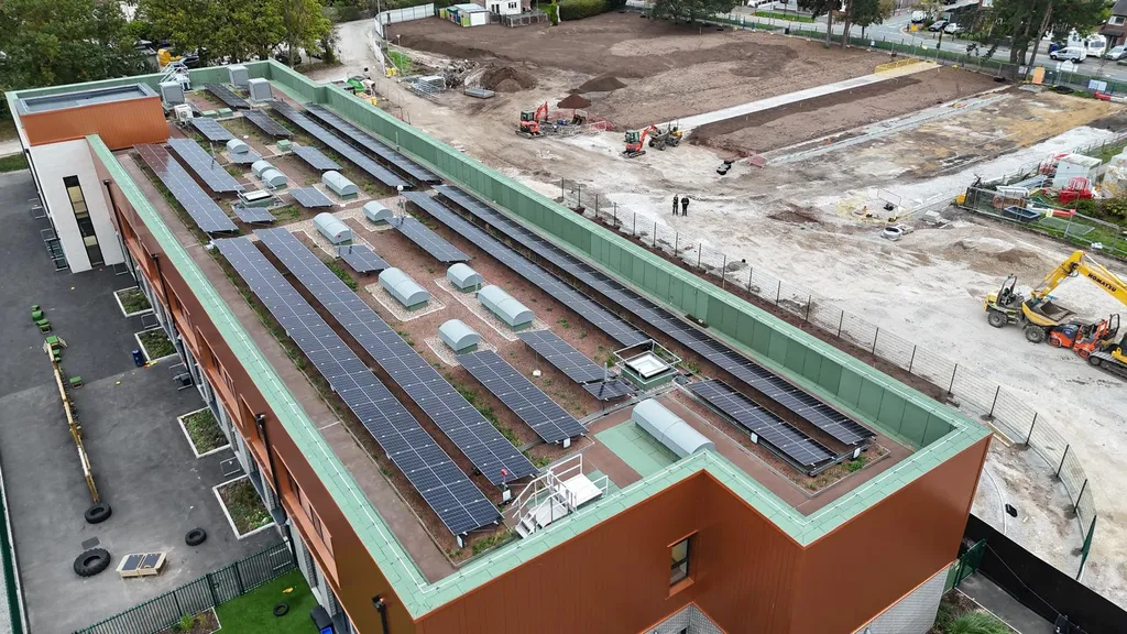 School rooftop solar panel array — flat roof overhead, Manchester