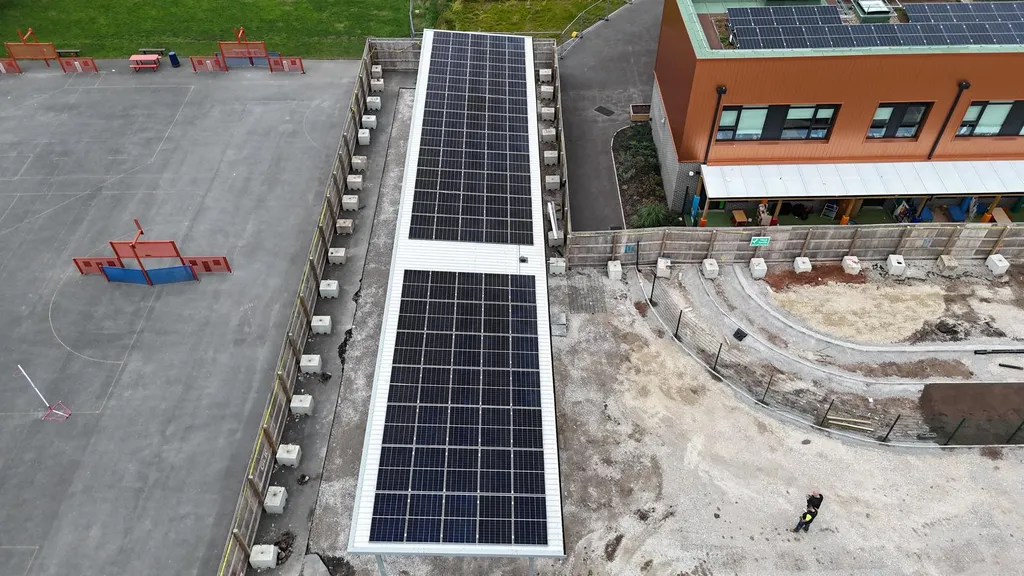 Solar canopy carport panels at school — close-up aerial, Manchester