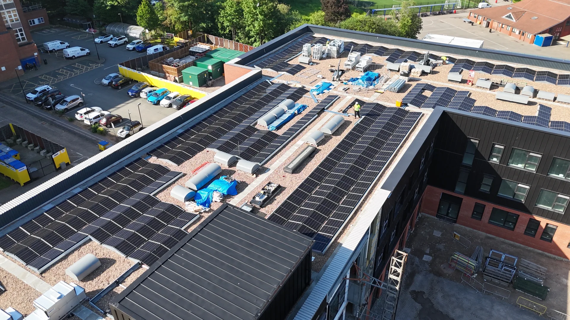 Commercial flat-roof solar PV installation at Wigan & Leigh College — Aiko 470W panels on an east-west ballasted tray system across the main building roof.