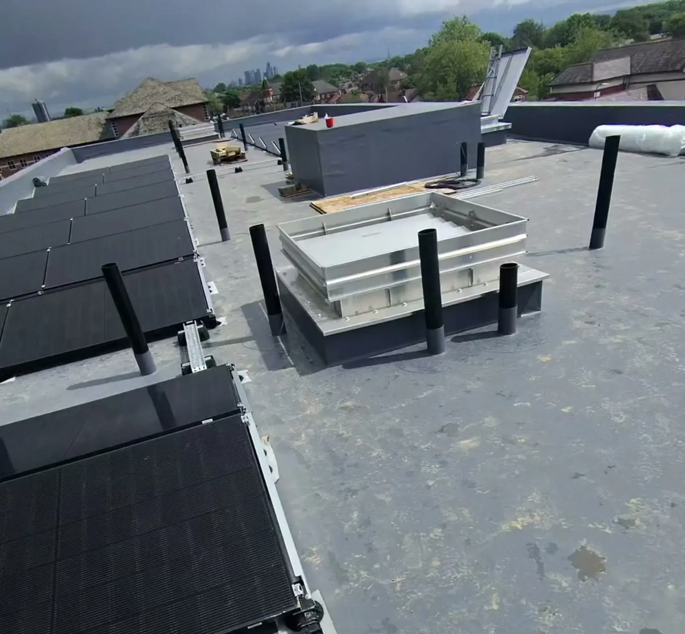 Apartment-block flat roof on the Sale new-build development — 425W solar panels on Esdec frames in an east-west orientation, with the Manchester skyline behind. Installed by Manchester Renewables.
