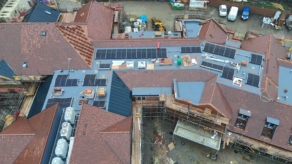 Solar panel array on care home roof — multiple pitched sections covered, Greater Manchester