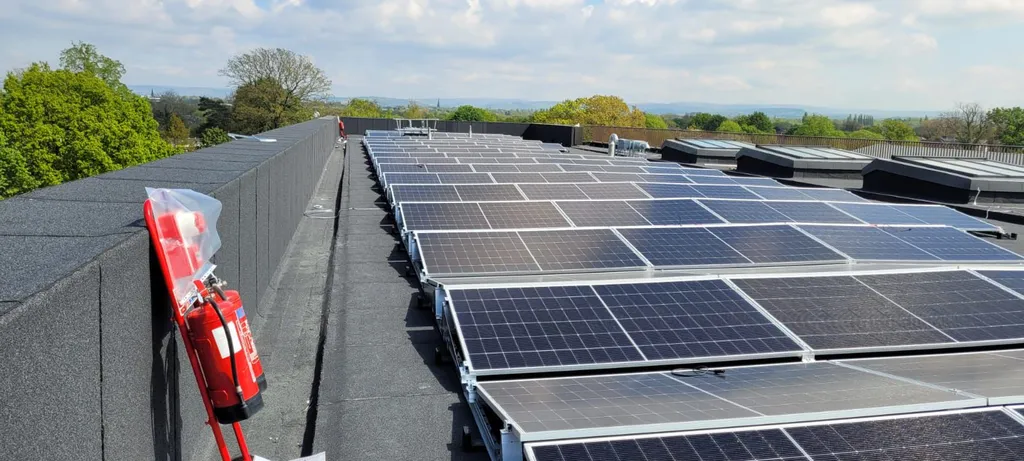 Commercial solar panels on college rooftop — drone shot showing rows of panels