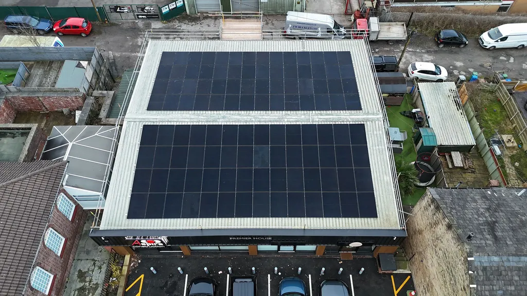 Commercial solar panels on factory rooftop — drone shot showing rows of panels, Manchester
