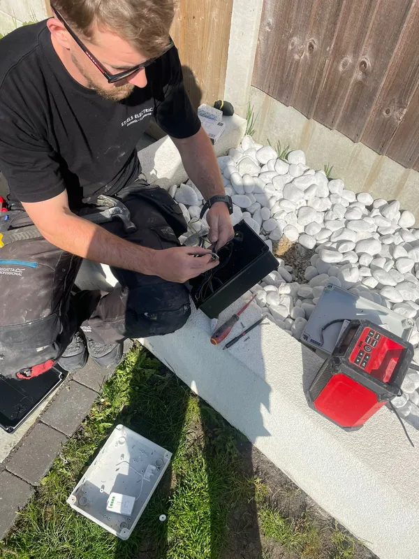 Steels Electrical engineer wiring an outdoor junction box during a garden lighting installation in Denton, Tameside