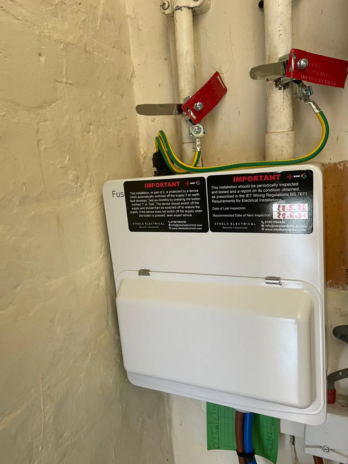 Finished Steels Electrical consumer unit in Hattersley with the cover on and inspection-date label fitted, gas and water bonding visible above
