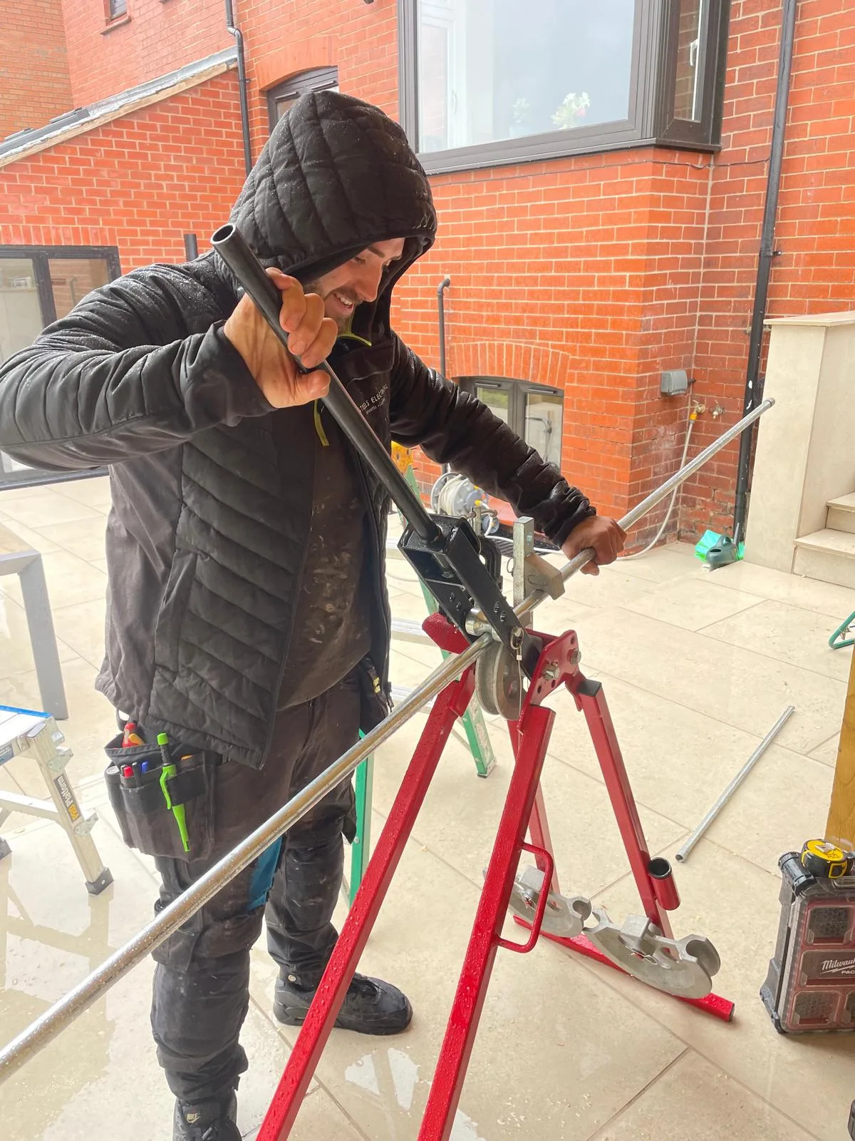 Steels Electrical electrician bending steel conduit for cable containment on a garden room installation in Hyde, Tameside