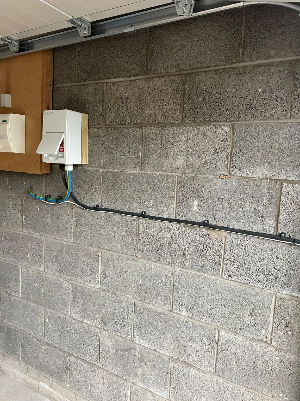 New EV charger consumer unit mounted in a Marple garage with the 6mm H07 supply cable clipped along the block wall